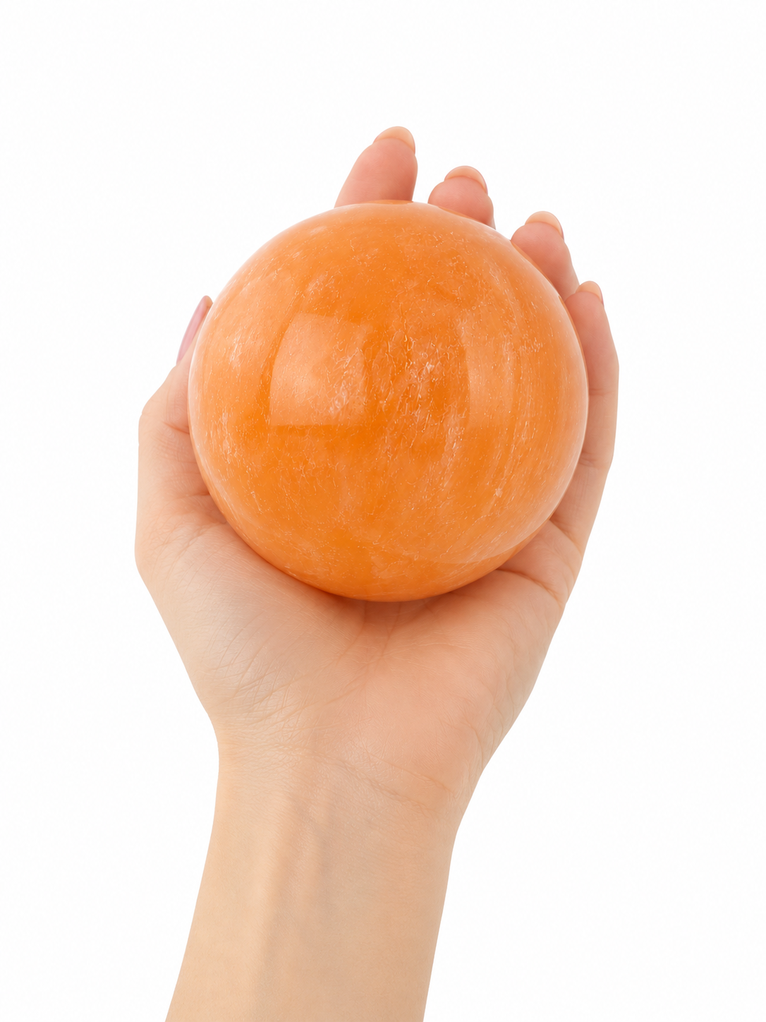 Mano de mujer sujetando esfera grande de selenita naranja