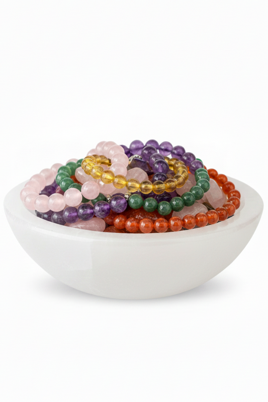 Cuenco de selenita 15cm con rodados coloridos y pulseras vista frontal ángulo bajo fondo blanco