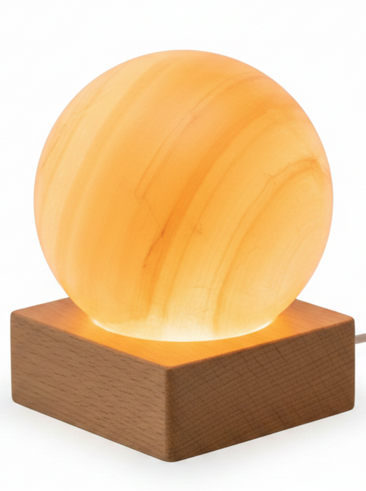 Lampara de selenita naranja sobre base LED de madera y fondo blanco