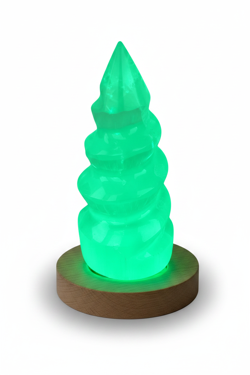 Torre de selenita unicornio sobre base LED de madera irradiando luz verde esmeralda